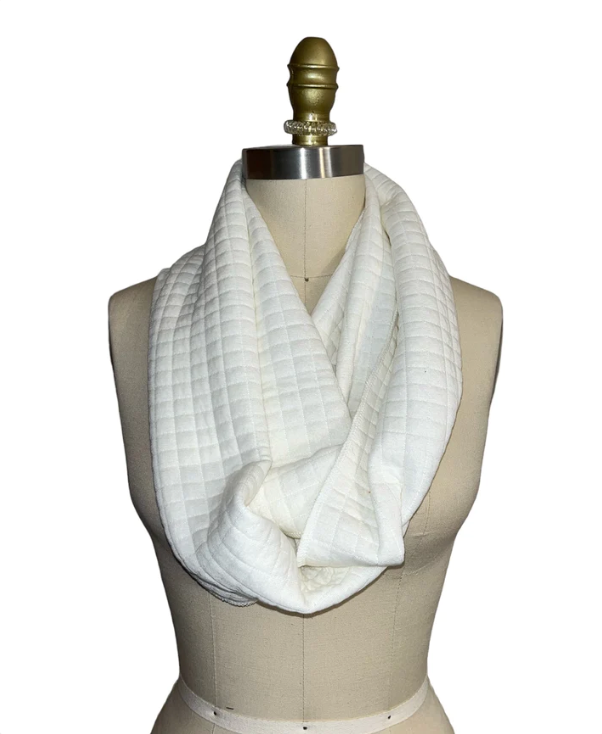 A white, quilted scarf resting on a female dress form. This scarf is made from discontinued fabric that otherwise would have been thrown away. SCAL provides this fabric a Second Chance at Life.